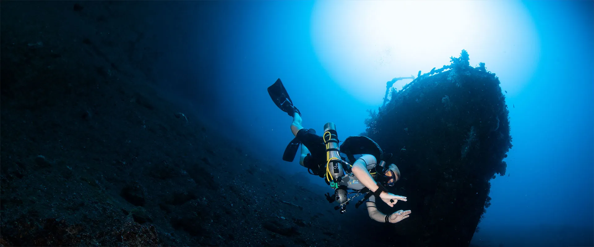 A diver hovering beside the coral-covered wreck off Tulamben