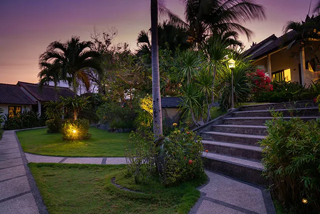 Beleuchtete Bungalows und tropischer Garten im Ocean Sun Resort bei Sonnenuntergang